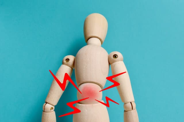 A wooden figure dummy with red lines around the lower back area, indicating pain.